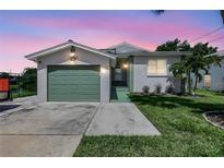 Charming single-story home with a well-manicured lawn, and a one car garage under a vibrant dusk sky at 6603 S Juanita St, Tampa, FL 33616