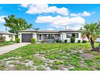Charming home featuring a well-maintained lawn, stone accents, and attached garage at 7305 Jasmine Blvd, Port Richey, FL 34668