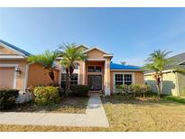 Charming single Gathering home boasting lush landscaping, mature palm trees and a double door entryway at 7705 Nottinghill Sky Dr, Apollo Beach, FL 33572