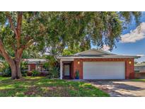 Charming brick home featuring a lush front yard, mature trees, and an attached two-car garage at 13029 111Th Ln, Largo, FL 33778