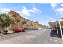 Beige two-story condominium complex with palm trees, parking spaces, and blue skies on a sunny day at 2525 W Bay Dr # B43, Belleair Bluffs, FL 33770