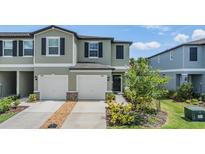 Charming townhome featuring a two-car garage, manicured lawn, and lush landscaping at 36414 Well Hill Way, Zephyrhills, FL 33541