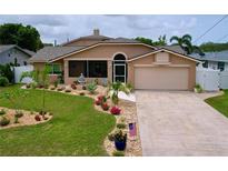 Charming single-story home with a well-manicured lawn and a welcoming screened entry at 386 Westwinds Dr, Palm Harbor, FL 34683
