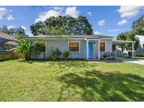 Charming single-story home featuring a bright blue door, covered parking, and a well-manicured lawn at 4009 S Renellie Dr, Tampa, FL 33611