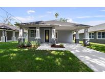 Charming single-story home with a well-manicured lawn, gray siding, and inviting front porch at 5705 N 20Th St, Tampa, FL 33610