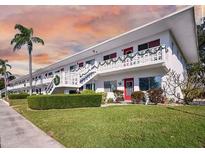 White two-story building with colorful red doors and green outdoor decor at 8425 112Th St # 203, Seminole, FL 33772