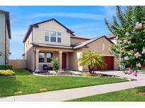 Charming two-story home featuring a manicured lawn, red garage door, and a welcoming front porch with white columns at 8747 Flourish Dr, Land O Lakes, FL 34637
