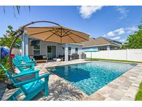 Backyard pool with patio, umbrella and plenty of seating for outdoor entertaining on a sunny day at 11307 Quiet Forest Dr, Tampa, FL 33635