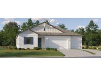 Charming home exterior featuring a two-car garage, blue shutters, and lush green lawn at 11546 Flourish Dr, Land O Lakes, FL 34637