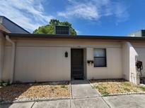 Inviting front entrance with a brown front door, stone landscaping, and an exterior wall unit at 1406 Arrowhead W Cir, Clearwater, FL 33759