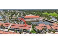 A captivating aerial view showcasing a beautiful red-roofed townhome community and the lovely waterfront area it neighbors at 2363 Hanover Dr, Dunedin, FL 34698