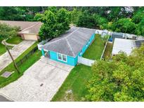 Charming turquoise home with a brick driveway, fenced yard and mature trees at 2715 Bel Aire Cir, Tampa, FL 33614