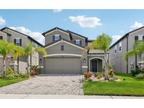 Charming two-story home features a well-manicured lawn, brick paver driveway, and neutral exterior paint at 37820 Beacon Brick Dr, Zephyrhills, FL 33540
