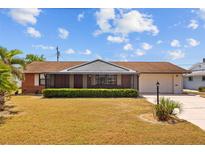 Charming single-story home with manicured landscaping, mature trees, and a vibrant red front door at 828 Fox Hills Dr, Sun City Center, FL 33573