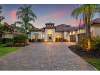 Stunning home featuring lush landscaping, a paver driveway, and a tile roof at dusk at 9712 Tree Tops Lake Rd, Tampa, FL 33626