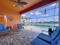 Covered patio featuring brick pavers, comfortable seating, ceiling fan and view of the pool and lake at 11614 Ashton Field Ave, Riverview, FL 33579