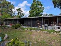 Exterior view of a home featuring a screened porch with ample seating and a well-maintained lawn at 12709 Greenland Dr, Riverview, FL 33579