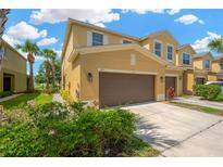 Inviting townhome featuring a two-car garage, manicured landscaping, and a warm, neutral color palette at 2022 Hawks View Dr, Ruskin, FL 33570