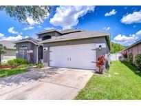 Single-story home featuring a well-manicured lawn, a two-car garage, and landscaped front yard at 31349 Philmar Ln, Wesley Chapel, FL 33543