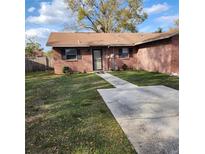 Charming brick home with a well-maintained lawn and concrete walkway leading to the front door at 5119 Hector Ct, Tampa, FL 33624