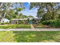 Charming single-story home features a bright blue front door, green lawn, and mature landscaping at 7219 4Th N Ave, St Petersburg, FL 33710