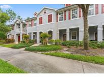Charming townhome featuring a well-maintained gray exterior, red shutters, and lush landscaping at 9418 W Park Village Dr # 105, Tampa, FL 33626