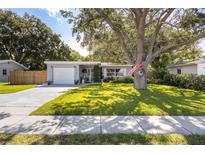 Charming single-story home with a lush front yard and mature tree, American flag and inviting curb appeal at 10095 Oakhurst Rd, Seminole, FL 33776