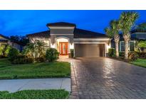 Charming home exterior featuring a paver driveway, lush landscaping, and a two-car garage at 11039 Calluna Dr, Odessa, FL 33556