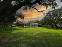 Expansive front lawn framing a well-maintained home with a column-supported front porch and mature trees at 13807 Eagles Rock Ct, Hudson, FL 34667