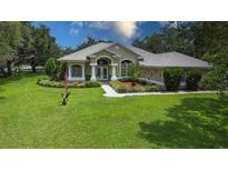 Charming one-story home with well-manicured lawn, mature trees, and elegant architectural details at 13807 Eagles Rock Ct, Hudson, FL 34667