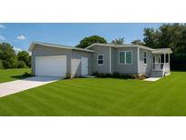Charming gray home featuring an attached garage and a well-maintained, expansive green lawn at 15591 Charmwood Dr, Hudson, FL 34667