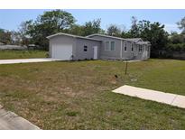 Well-maintained single-Gathering home featuring a grey facade, attached garage, and front lawn at 15591 Charmwood Dr, Hudson, FL 34667