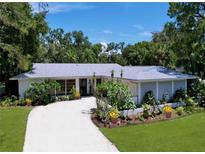 Charming single-story home with a well-manicured front yard and a winding driveway at 1861 Royal Oak E Pl, Dunedin, FL 34698