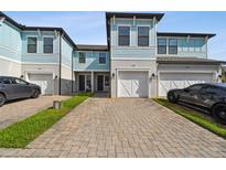 Charming two-story townhomes with light blue accents and brick paved driveways at 2432 Golden Pasture Cir, Clearwater, FL 33764