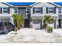 Charming two-story townhome featuring a two-car driveway, one car garage, and tropical landscaping at 2801 Midnight Pearl Dr, Sarasota, FL 34240