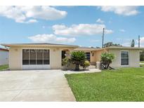 Charming single-story home with lush landscaping, a driveway, and a screened-in garage in a well-maintained community at 3401 Pinon Dr, Holiday, FL 34691