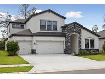 Beautiful two-story home featuring a three car garage and stone archway over the entryway at 3458 Yellow Leaf Cir, Spring Hill, FL 34609