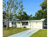 Charming single-story home with white exterior, landscaped yard, and a driveway leading to an attached garage at 3542 Monticello St, New Port Richey, FL 34652