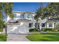 Elegant two-story home with a white exterior, a basketball hoop, a manicured lawn, and a paver driveway at 534 Ladrone Ave, Tampa, FL 33606