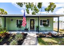 Charming home entrance with an American flag, green walls, and well-maintained landscaping at 6411 S Clark Ave, Tampa, FL 33616