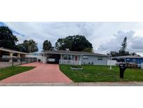 Charming single-story home featuring a covered parking, a well-maintained lawn, and a cozy front porch at 7416 Manchester Ln, Tampa, FL 33619