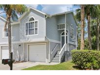 Charming two-story townhouse with a one-car garage, front steps and porch, and attractive tropical landscaping at 7630 Sailwinds Pass, Port Richey, FL 34668