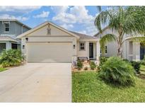 Charming single-Gathering home showcasing a well-manicured lawn and a two-car garage on a sunny day at 8310 Hardy Bay Loop, Wesley Chapel, FL 33545