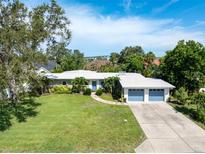 Charming single-story home with a well-manicured lawn, lush landscaping, and a two-car garage at 120 Crestwood Ln, Largo, FL 33770