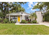 Charming single-story home with a bright yellow door and well-manicured landscaping at 1226 E Henry Ave, Tampa, FL 33604