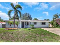 Charming single-story home featuring a well-maintained lawn, palm trees, and a covered entryway at 1420 Temple St, Clearwater, FL 33756