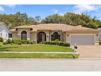 Charming single-story home featuring a well-manicured lawn, arched windows and a brick-paved driveway at 14228 Teasdale Ave, Hudson, FL 34667