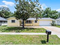 Charming yellow single-story home with a well-manicured lawn and mature tree in a sunny neighborhood at 2481 12Th Sw Ave, Largo, FL 33770