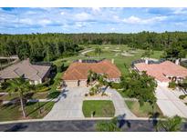 Stunning aerial view of single-story home with tile roof, golf course views and mature landscaping at 3337 Crescent Oaks Blvd, Tarpon Springs, FL 34688