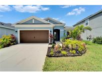 Inviting single-story home featuring a well-manicured lawn and a charming, warm-toned garage door at 5415 Limelight Dr, Apollo Beach, FL 33572